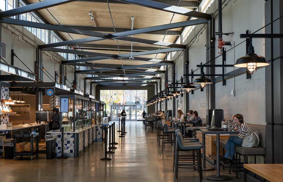 Interior view of the 1901 Marketplace dining hall at Cal Poly with students eating and working at tables