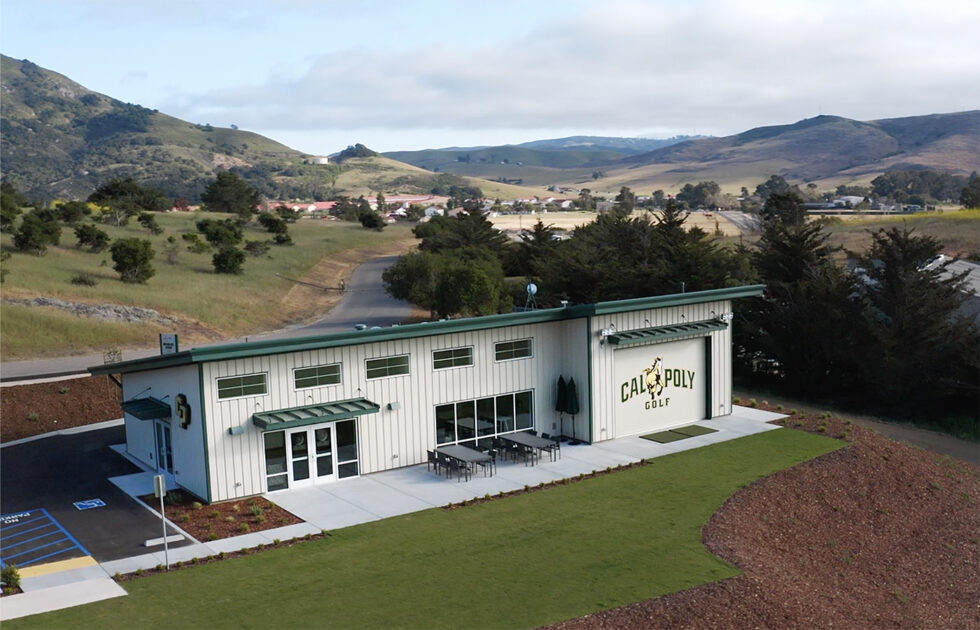 Exterior view of the Cal Poly Golf training center surrounded by hills and landscaped greenery