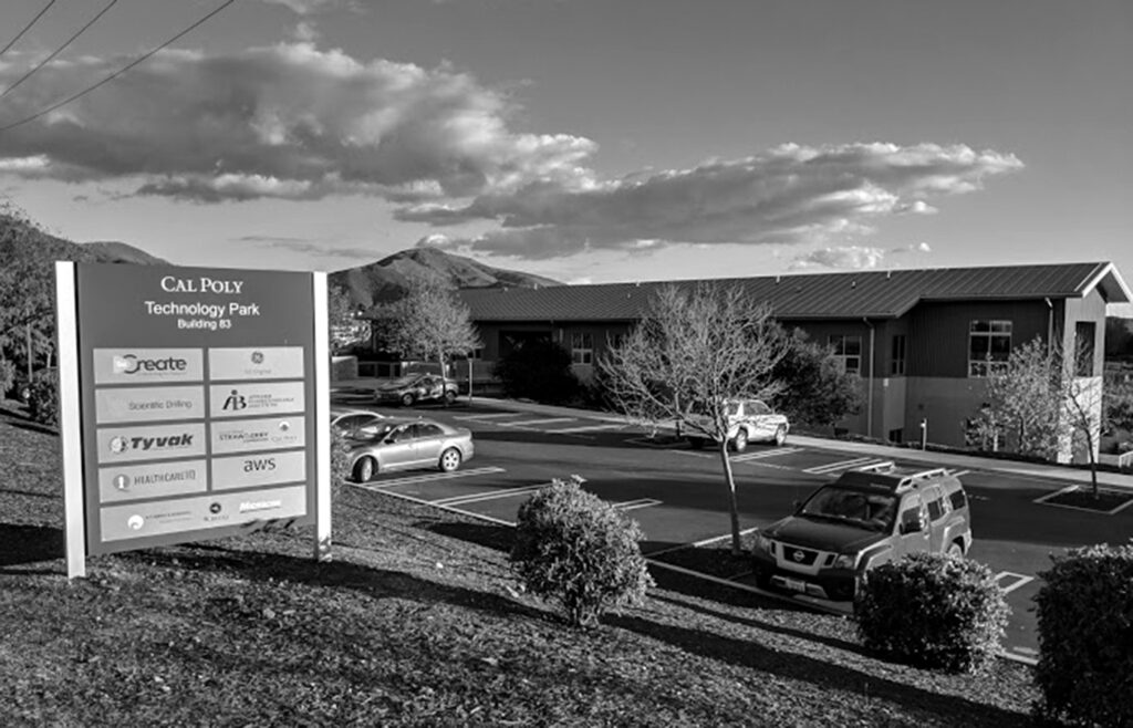 Black and white image of Cal Poly Technology Park in the early 2000s with signage for various companies and parked cars.
