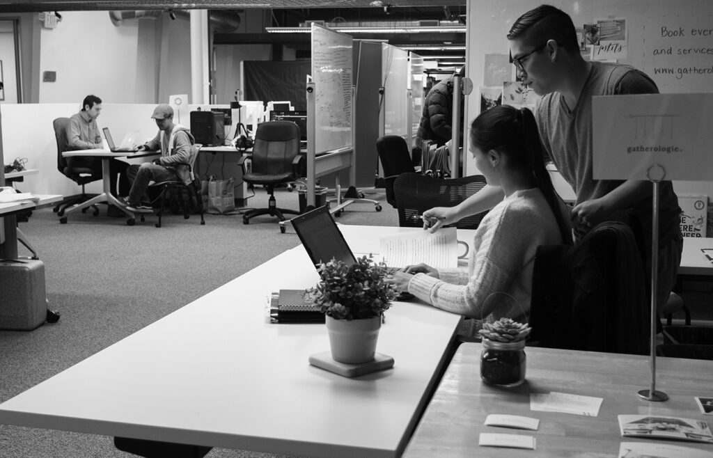 Students collaborating inside a modern open-plan campus office space at Cal Poly, surrounded by whiteboards and workstations.