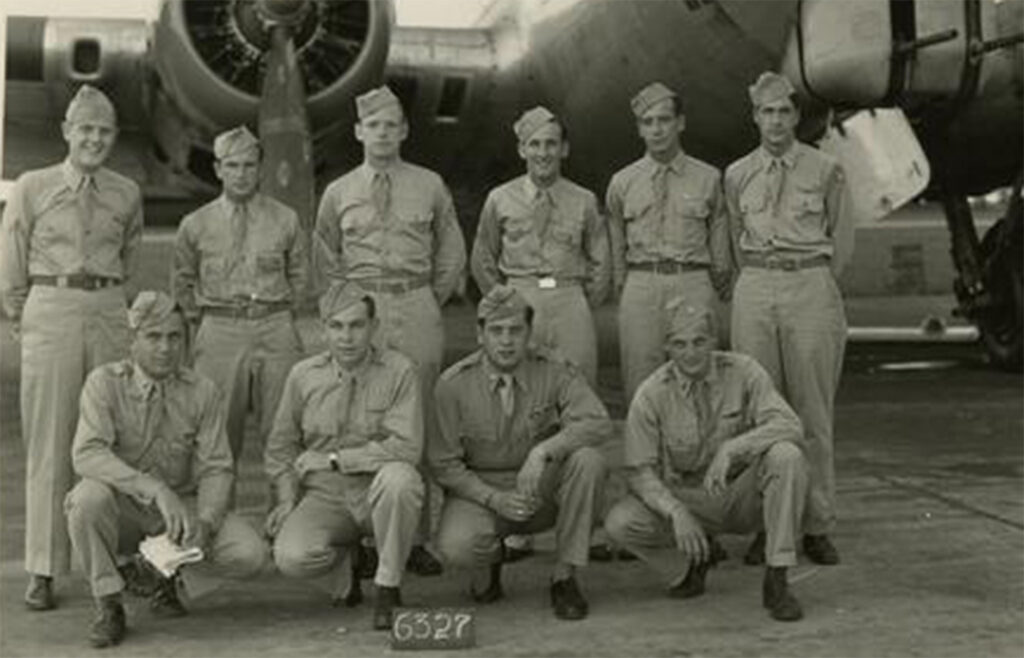 Historic black and white photo of World War II-era flight school cadets in uniform posing in front of a military aircraft.