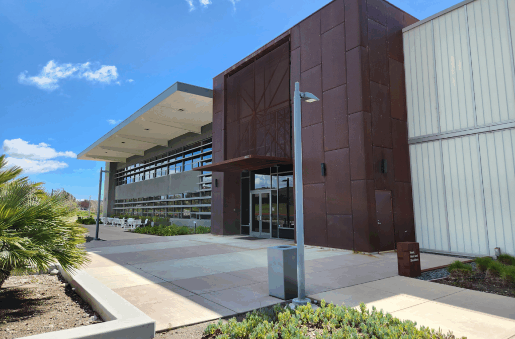 Modern Cal Poly campus building with metal and rust-colored panels under a blue sky.