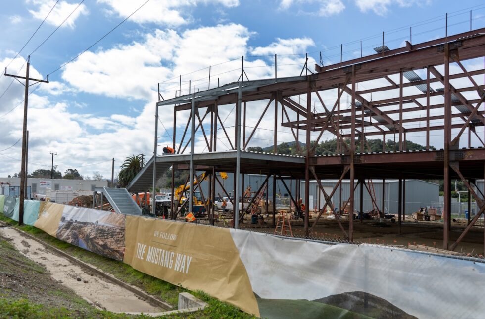 Steel frame under construction at Cal Poly Tech Park with banner reading “The Mustang Way.”